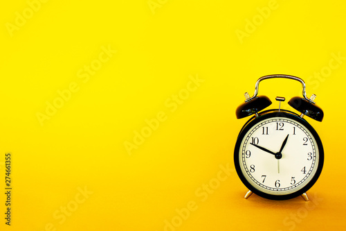 Retro style clock alarm clock on yellow background