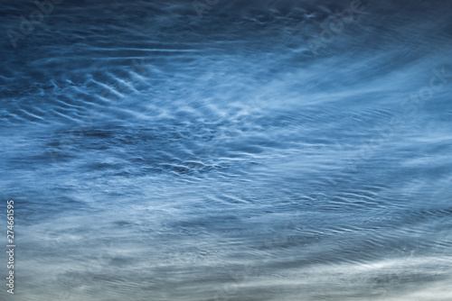 Close up of NLC: noctilucent clouds. Beautiful waves and ripples of silvery blue night shining clouds around midnight.