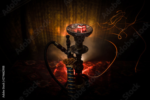 Hookah hot coals on shisha bowl on dark foggy background. Stylish oriental shisha. photo