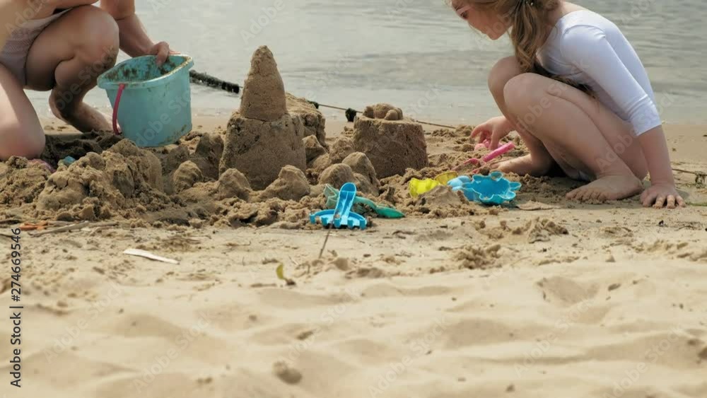Mom and daughter are playing on the beach, building a sand castle. Summer sunny day. vacation Mom and daughter are playing on the beach, building a sand castle. Summer sunny day. vacation