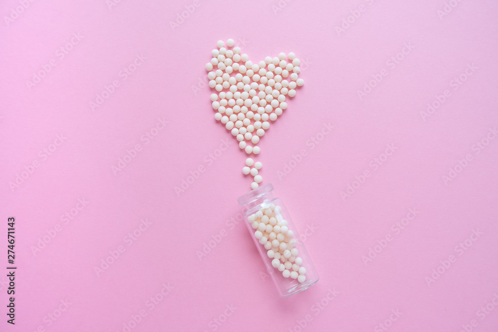 Heart made of homeopathic globules and glass bottle on pink background. Alternative Homeopathy medicine herbs, healtcare and pills concept. Flatlay. Top view. copyspace for text Heart made of homeopathic globules and glass bottle on pink background. Alternative Homeopathy medicine herbs, healtcare and pills concept. Flatlay. Top view. copyspace for text