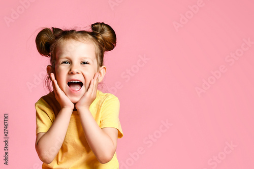 Portrait of little girl holding hands on head  screaming with opened mouth and crazy expression. Surprised or shocked face