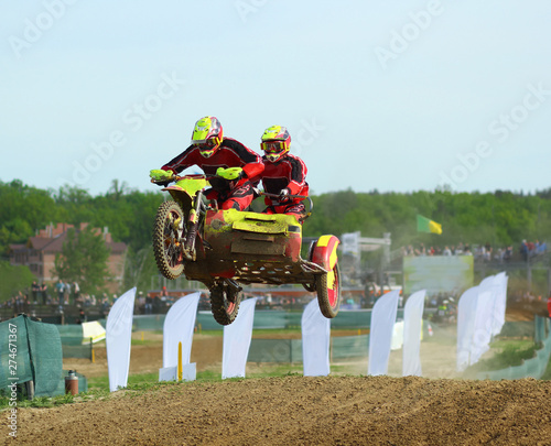 Sidecar motocross athletes in the air jump on the dirt track  photo