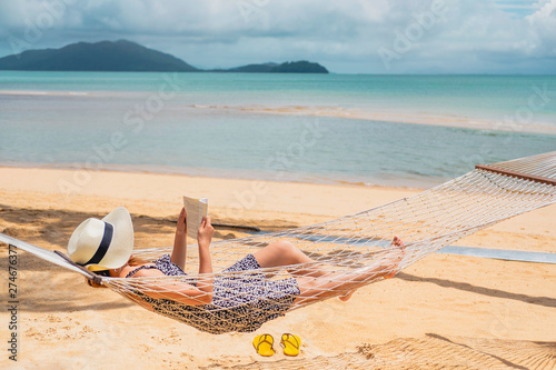 Woman reading a book on hammock beach in free time summer holiday