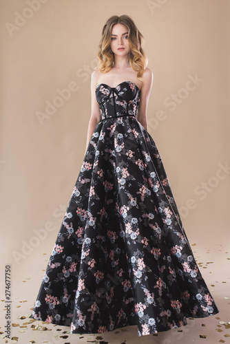 Fotografie, Obraz Beautiful girl in evening elegant dress posing on paper beige studio background