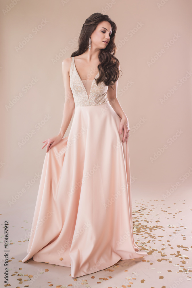 Beautiful girl in evening elegant dress posing on paper beige studio background full length portrait Beautiful girl in evening elegant dress posing on paper beige studio background full length portrait