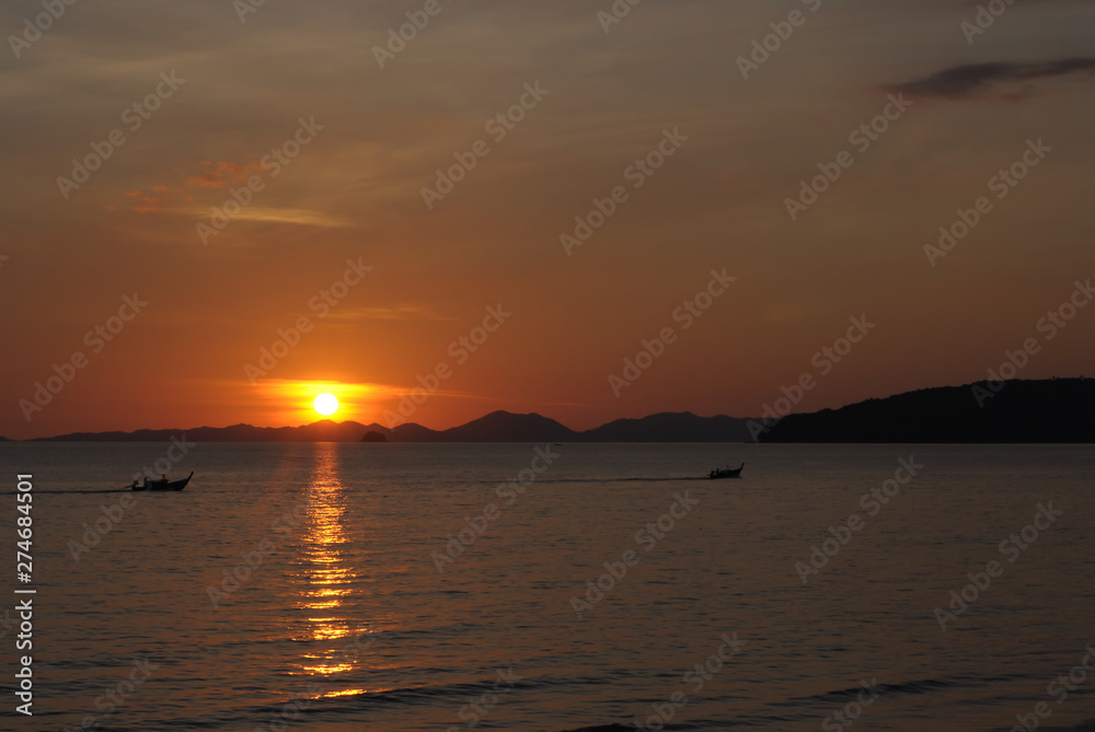 Tropical sunset, ship silhouette in ocean over evening sunlight