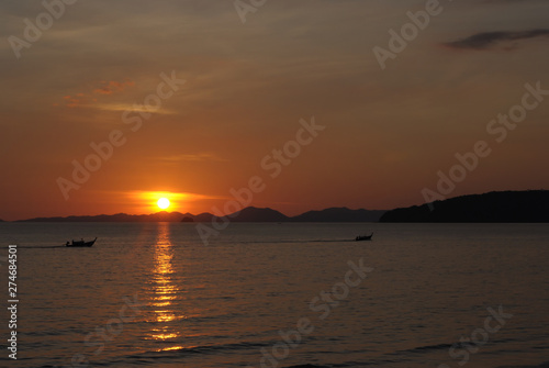 Tropical sunset, ship silhouette in ocean over evening sunlight