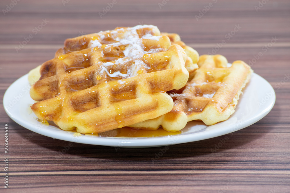 Viennese waffles sprinkled with powdered sugar and drizzled with honey. Viennese waffles sprinkled with powdered sugar and drizzled with honey.