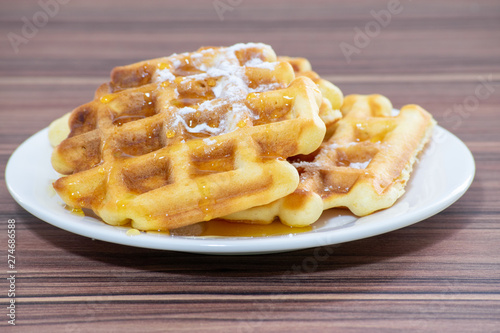 Viennese waffles sprinkled with powdered sugar and drizzled with honey.