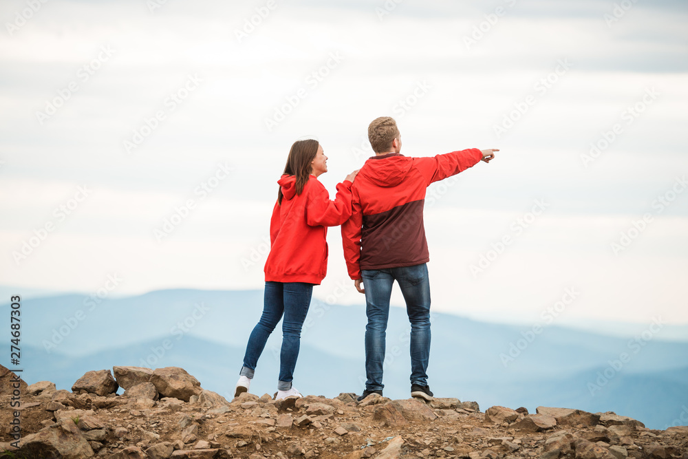 Young couple looks in the same direction, into the distance. Rear view. Loving couple. a romantic couple in love stands together on a mountain. silhouettes of a young man and a woman on vacation.