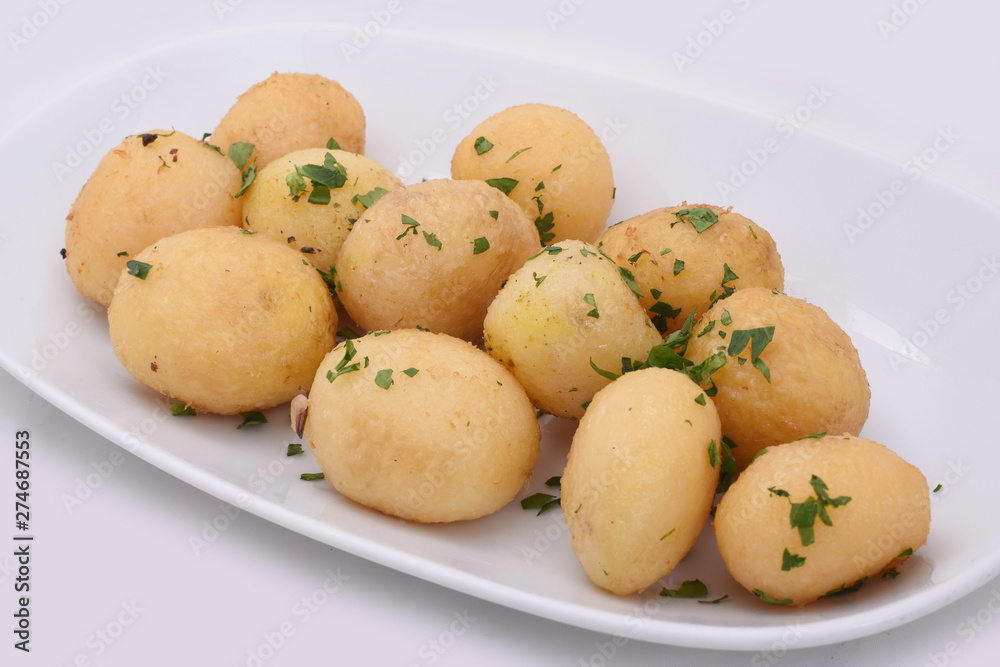 Young potatoes cooked whole deep-fried. On a white plate isolated on white background. Young potatoes cooked whole deep-fried. On a white plate isolated on white background.
