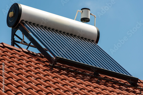 Solar water heater boiler on rooftop close up shot, blue sky background.