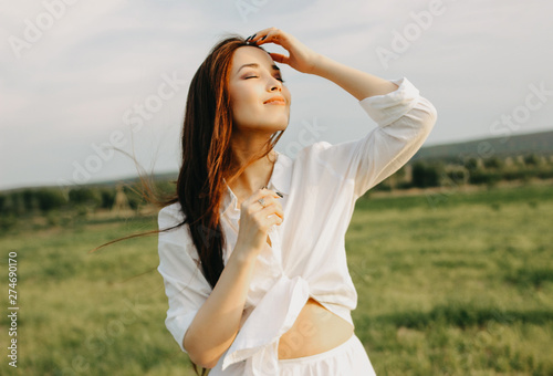 Portrait of beautiful carefree long hair girl in white clothes on field at sunset. Sensitivity to nature concept #274690170