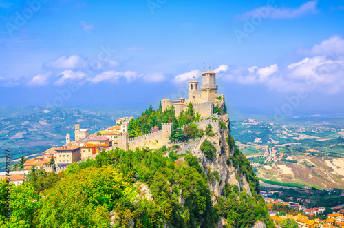 Republic San Marino Prima Torre Guaita first fortress tower with brick walls on Mount Titano stone rock with green trees  aerial top panoramic view of landscape valley and hills of suburban district