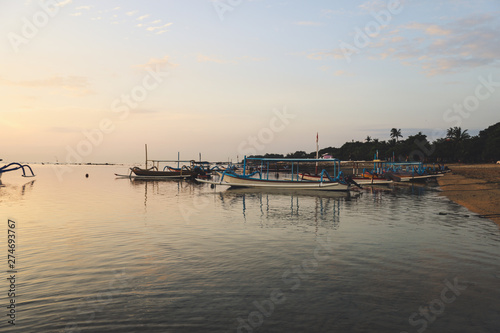 Sunrise view at Sanur Beach, Bali island, Indonesia. Traditional Balinese jukung fishing boats in the port