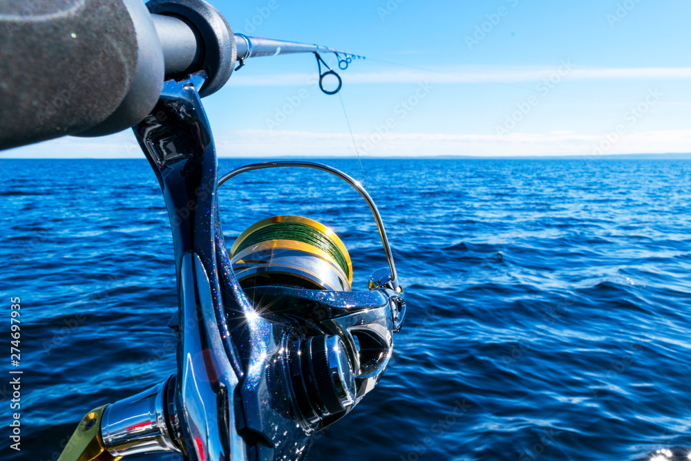 Fishing rod spinning with the line close-up. Fishing rod in rod holder in  fishing boat due the fishery day. Fishing rod rings. Fishing tackle. Fishing  spinning reel. Stock Photo