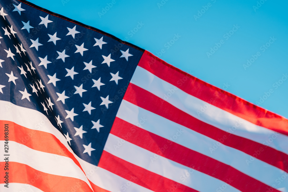 Obraz premium American flag in a blue sky, close up. Symbol of Independence Day fourth of July in USA
