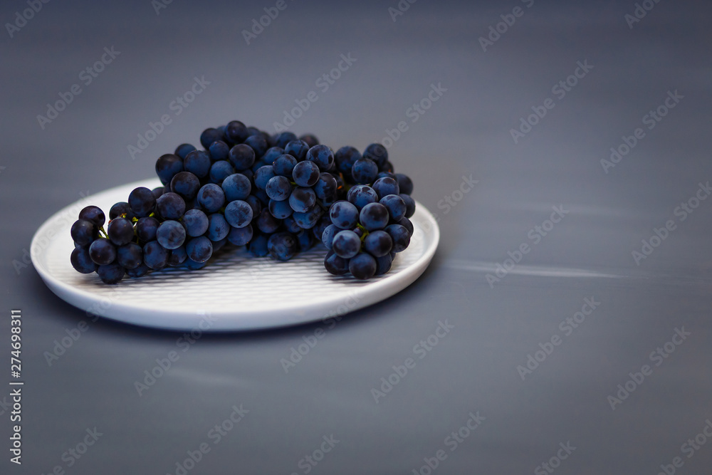 beautiful black blue grapes Isabella lies on a white plate beautiful black blue grapes Isabella lies on a white plate