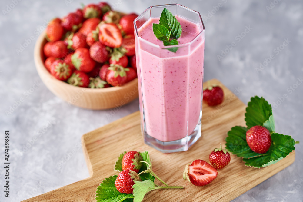 Smoothie with summer strawberry in glass jar and fresh berries on a gray background Smoothie with summer strawberry in glass jar and fresh berries on a gray background