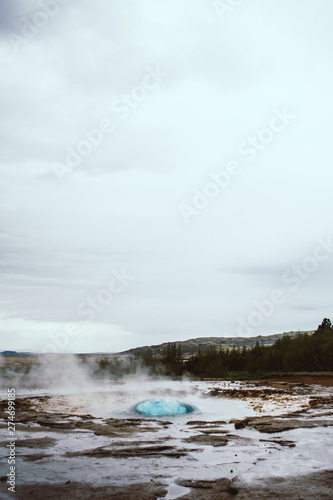 The turquoise blue boiling bubble and white steam of the famous Strokkur Geyser In Iceland right before eruption.