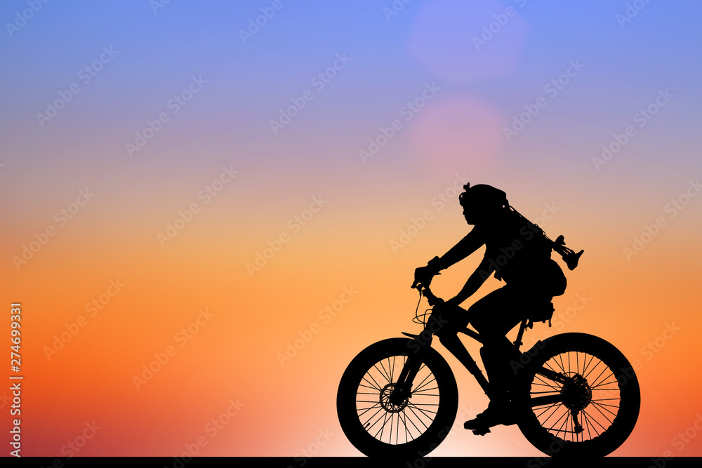 Fototapeta premium Silhouette man and bike relaxing on blurry sunrise sky background.
