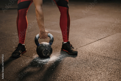 Closeup of sports woman holding kettlebell while crossfit training. Female lifting heavy weights.