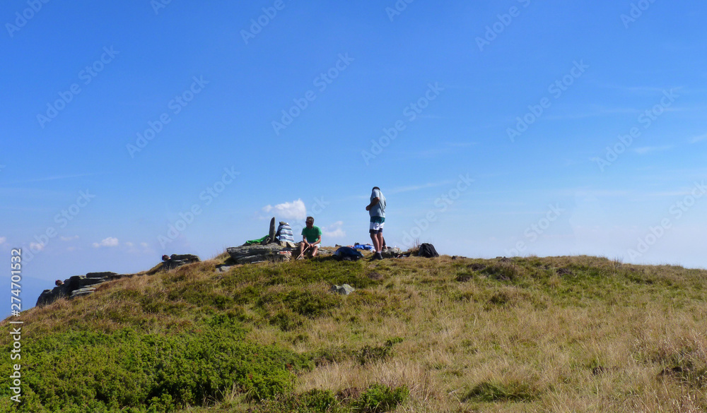 People hiking on alpine meadows on mountains, withered grass but deep blue sky, Carpathian mountain chains