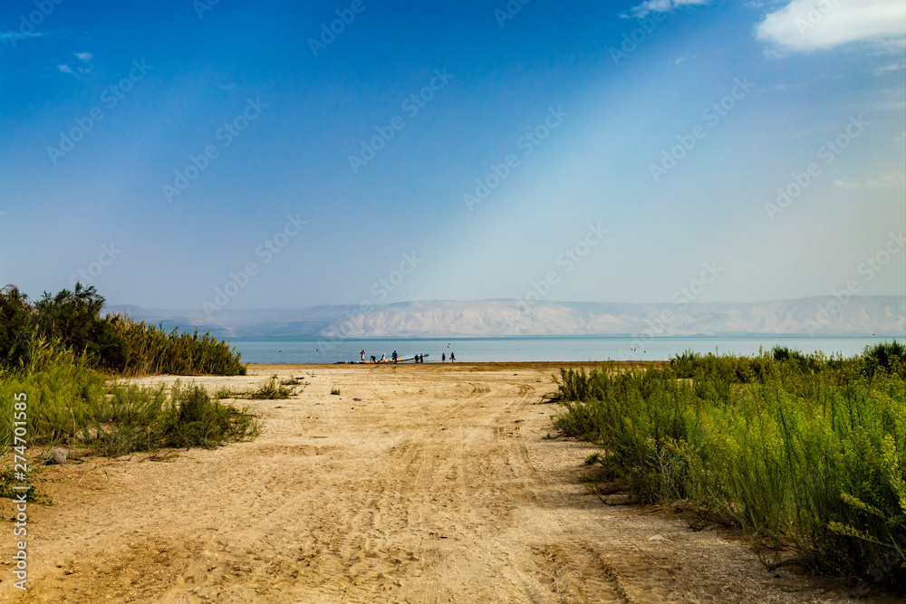 View of the sea of Galilee (Lake Tiberias, Kinneret or Kinnereth), beach with tire tracks and pontoon pier. The lowest freshwater lake on Earth. Israel.