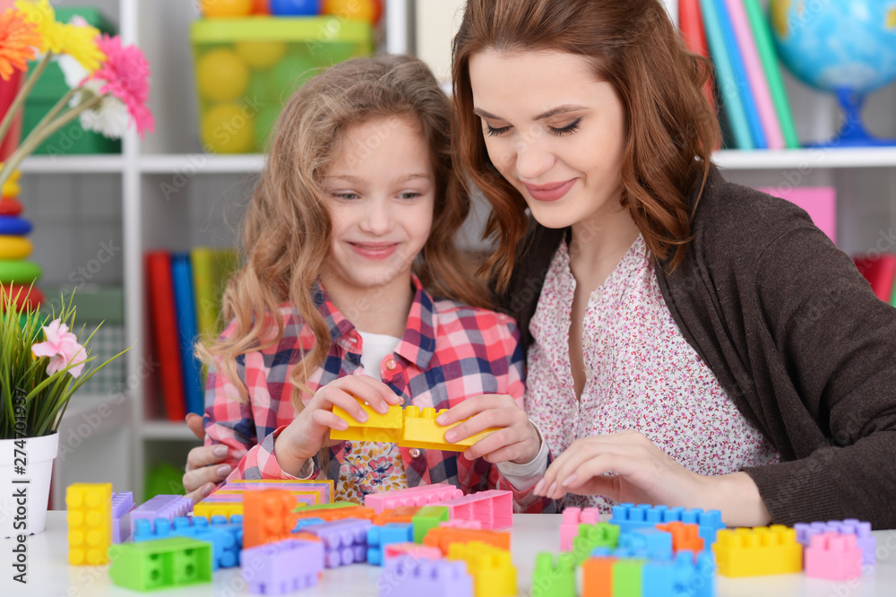 Cute little girl and her mother playing colorful plastic blocks