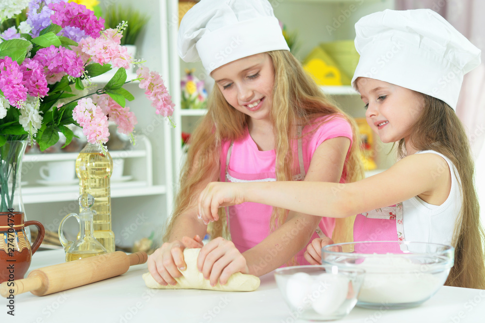 Portrait of cute girls in chefs hats making dough in the kitchen at home Portrait of cute girls in chefs hats making dough in the kitchen at home