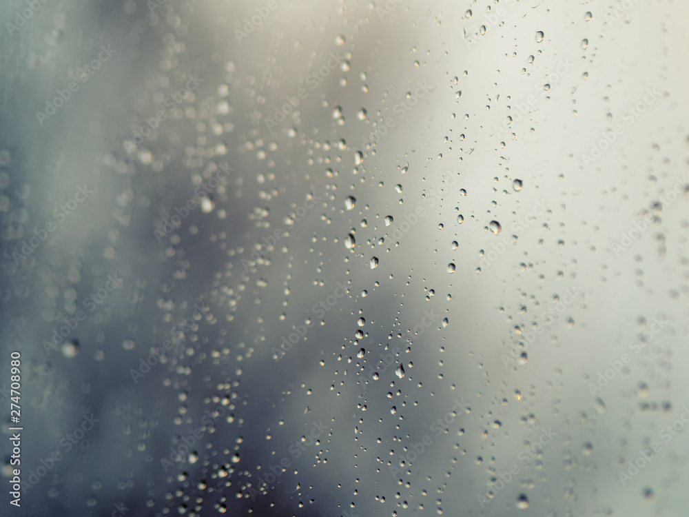 Raindrops on the surface of window glass with a blurred background.