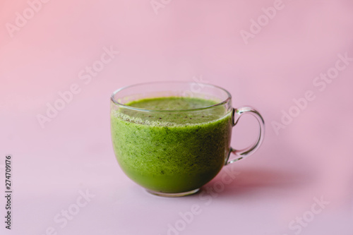 Healthy green smoothie with kiwi in a glass Cup on a pink background