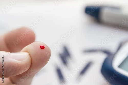 Man using lancet pen on finger to checking blood sugar level by blood glucose meter. Diabetes concept. Closeup, selective focus