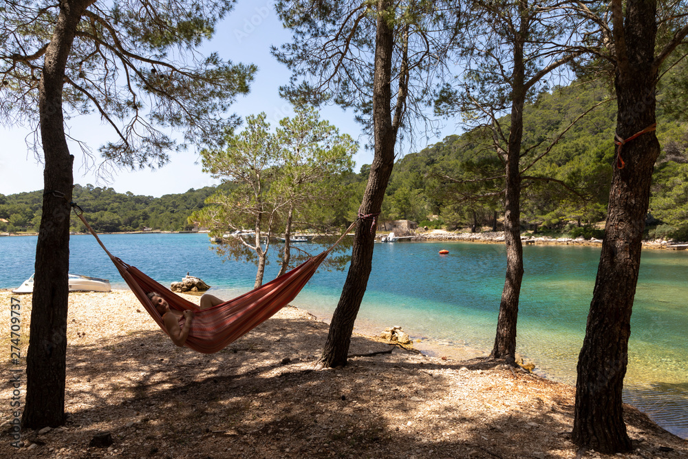 Woman relaxing in the hammock on a hot sunny day on the island lastovo, croatia
