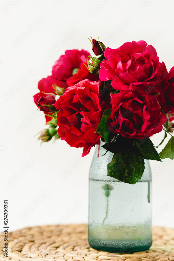 Obraz premium Stunning composition of colorful roses in a vase on a wicker napkin