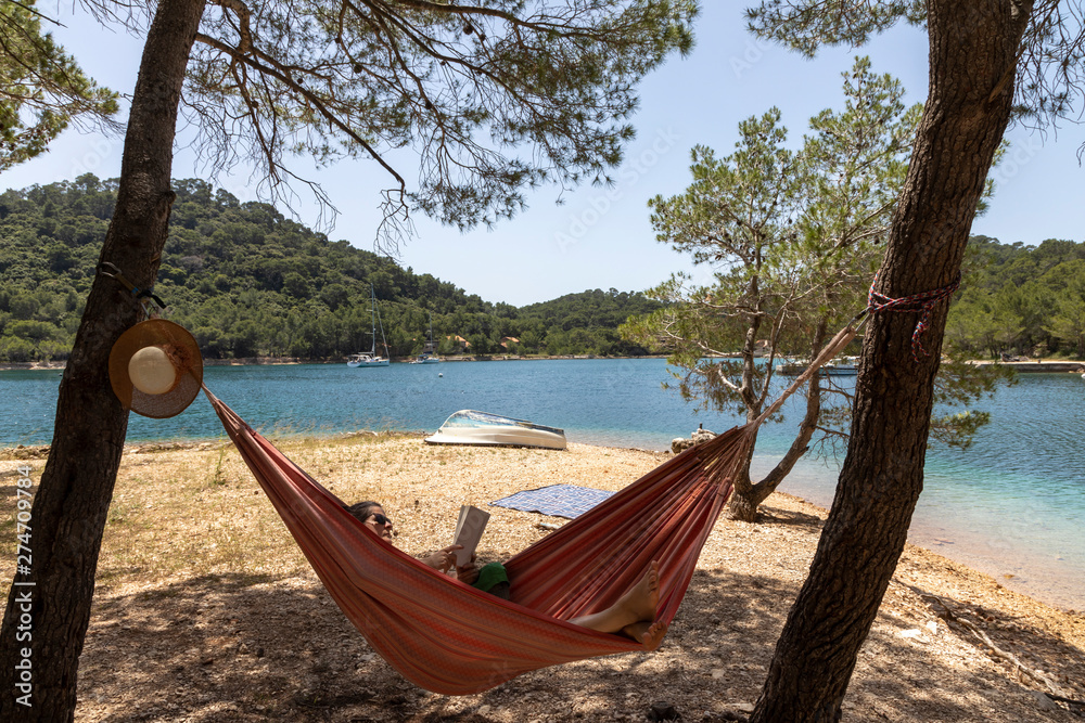 Woman relaxing in the hammock on a hot sunny day on the island lastovo, croatia