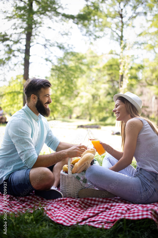 Happy young couple enjoying a picnic in the park together Happy young couple enjoying a picnic in the park together