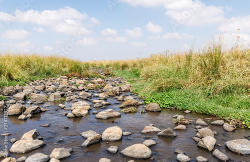 Shallow river flowing near the remnants of the early Bronze Age megalithic complex of the early Bronze Age - Wheels of Spirits - Rujum Al-Hiri - Gilgal Rephaeem - on the Golan Heights in Israel