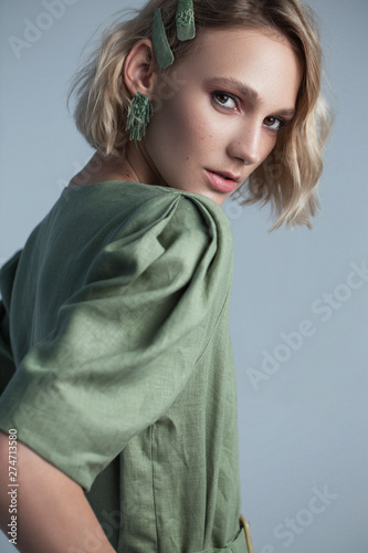 Fashion portrait of blonde female model on grey background. stylish green clothes and accessories. concept of garmonical style and atmosphere