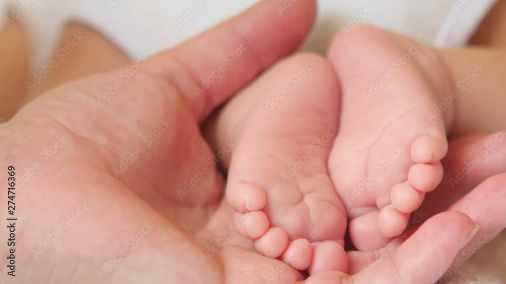 Mother gently holds in her hand the small legs of her newborn baby, motherhood. Mom and her Child. Happy Family concept. Mother gently holds in her hand the small legs of her newborn baby, motherhood. Mom and her Child. Happy Family concept.