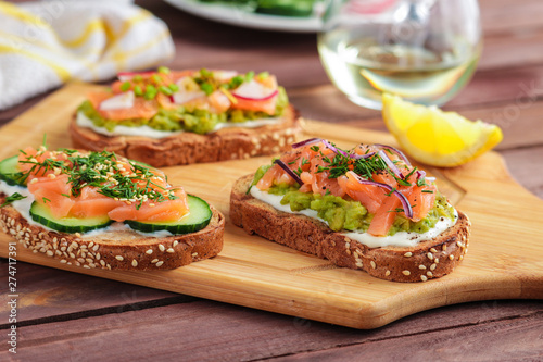 homemade open sandwiches with  bread  salmon cream cheese sliced cucumber dill avocado on wooden cutting board 