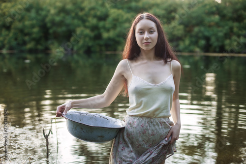 Fototapeta Naklejka Na Ścianę i Meble -  Portrait of a beautiful young laundress in a lake.