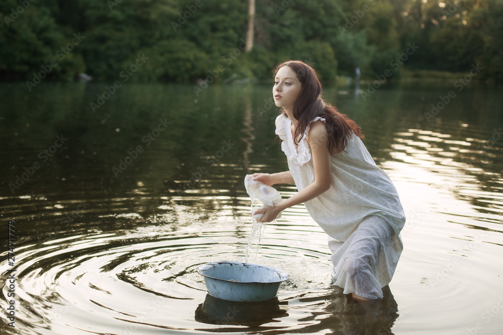 Young laundress in nightie washing clothes in the river. Stock Photo