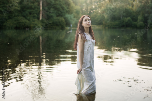 Young woman in nightie is standing in the river. © Petro