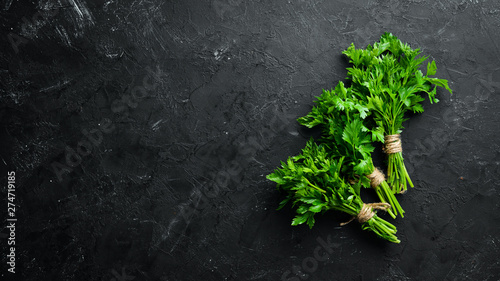 Green parsley on a black stone background. Top view. Free space for your text. photo