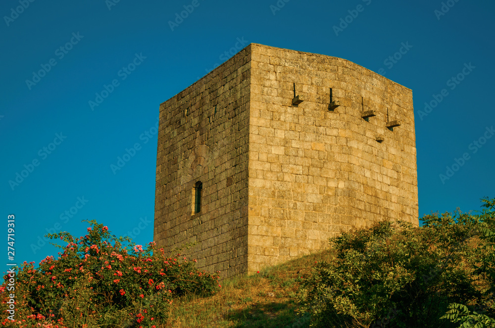 Stone square tower over rocky hill on sunset