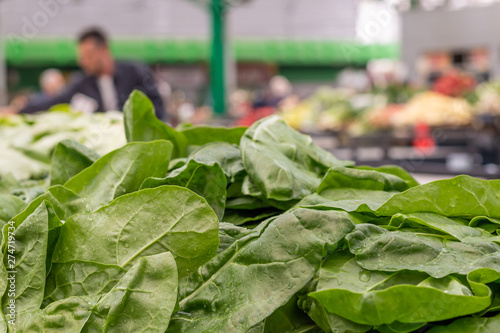 Pile of fresh green chard leaves on the marketplace counter in Belgrade. Blurred sellers and customers on background