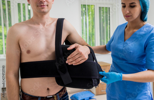 Nurse putting a sling on patients arm that is broken. Injury photo