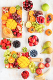 Vegan breakfast, cut colorful rainbow fruits, strawberries raspberries oranges plums apples kiwis grapes blueberries mango persimmon, copy space, selective focus